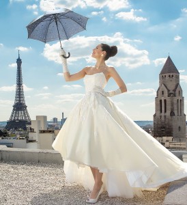 Bride holding a wedding umbrella posing having Eiffel Tower as a backdrop